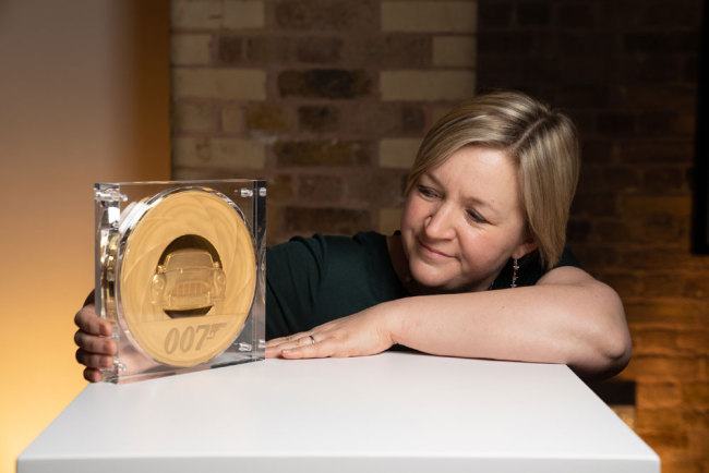The Royal Mint ontwerpster Laura Clancy samen met de 7 kilogram wegende James Bond-munt.