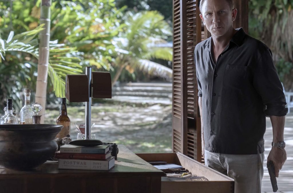 James Bond (Daniel Craig) in zijn huis in Jamaica. Op de tafel vermoedelijk een Leica Q2 fototoestel.